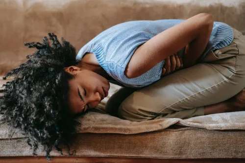 A woman experiencing period cramps, showing the discomfort and pain many women face during menstruation