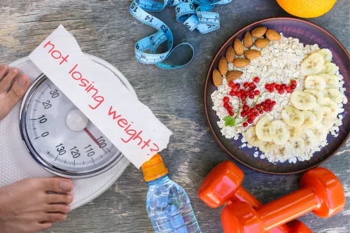A visual of a person standing on a scale, surrounded by healthy food and exercise gear, highlighting the frustration of not losing weight despite healthy habits.