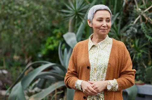 Woman in a cozy cardigan standing outdoors, reflecting a peaceful moment in perimenopause.